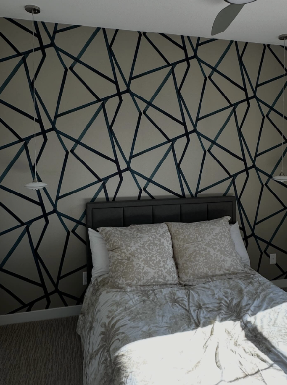Geometric accent wall behind a bedroom bed